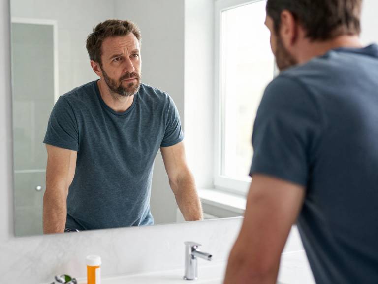 Мужчина оценивает потерю мышечной массы в зеркале